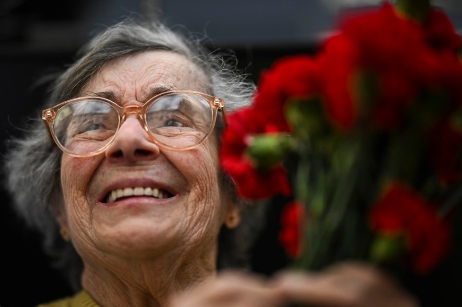Celeste Caeiro, que entregou cravos vermelhos aos militares durante a Revolução dos Cravos em 25 de abril de 1974, segura um buquê de cravos durante um desfile militar em comemoração ao 50º aniversário da Revolução
