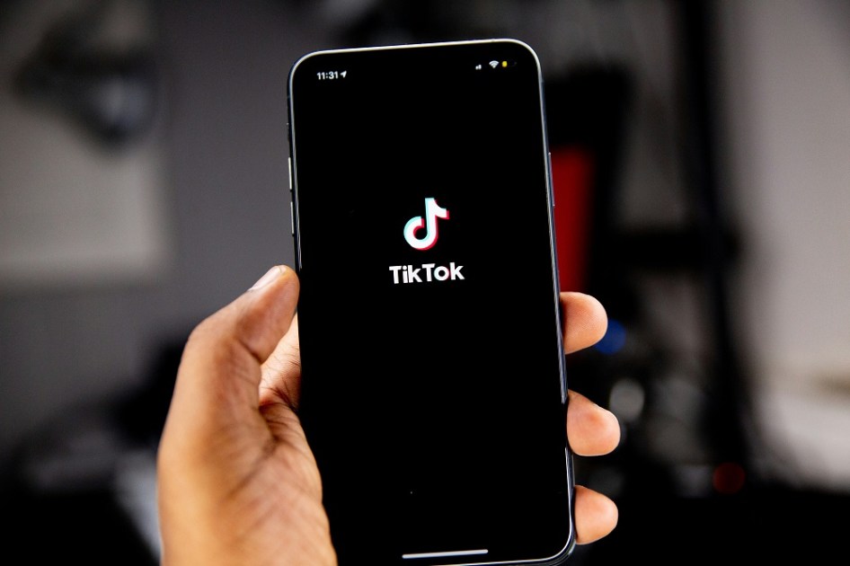 Mão segurando celular com símbolo do TikTok