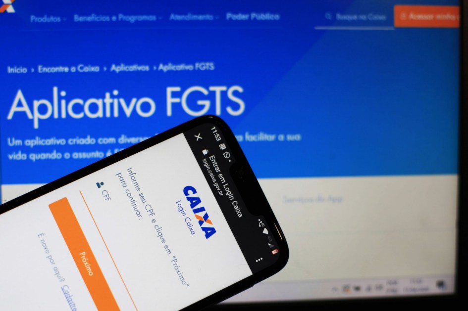 Celular e tela de computador abertos na aba do FGTS do site da Caixa