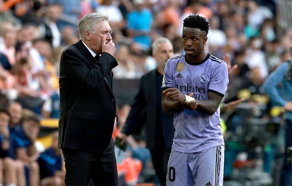 O técnico italiano do Real Madrid, Carlo Ancelotti (E), conversa com o atacante brasileiro Vinicius Junior, do Real Madrid, durante a partida