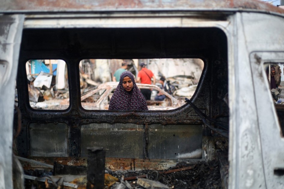 A Palestinian girl looks inside a cr carcass at the site of an Israeli airstrike on tents for displaced people two days earlier in the courtyard of Al-Aqsa Martyrs Hospital in Deir al-Balah in the central Gaza Strip, on October 16, 2024. A spokesman for the Palestinian Civil Defence in Gaza said the October 14 strike had killed four people and wounded many more, noting it was the seventh time an attack had hit the "tents for displaced people inside the walls of Al-Aqsa Martyrs Hospital".