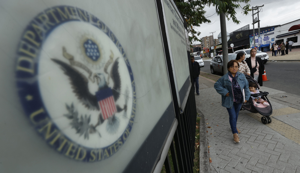 Cidadãos colombianos solicitantes de visto para os Estados Unidos caminham em frente à embaixada americana