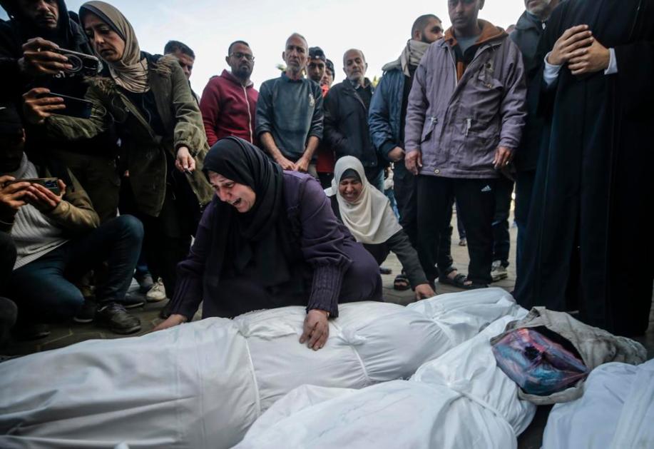 Mulheres palestinas lamentam sobre os corpos cobertos dos membros de uma família palestina mortos em um ataque aéreo israelense