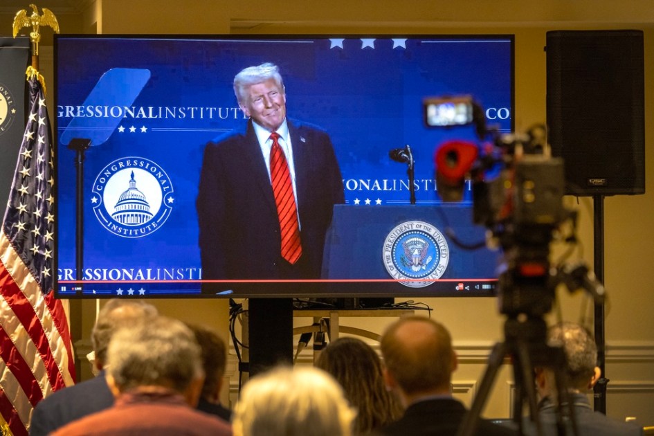 Membros da mídia acompanham em uma tela de TV o discurso do presidente dos Estados Unidos, Donald J. Trump, transmitido da sala de imprensa durante a Conferência Republicana de 2025 no resort Trump National Doral, em Miami, Flórida