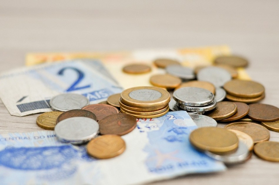 Notas e moedas de baixo valor espalhadas em mesa
