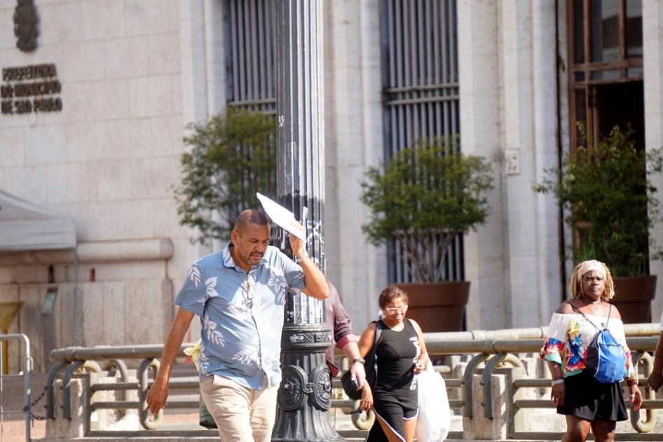 Pedestre se protege do sol no Viaduto do Chá, na região central de São Paulo
