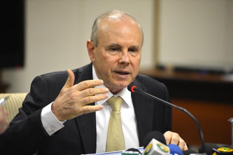 Guido Mantega: homem branco idoso fala em frente a microfone