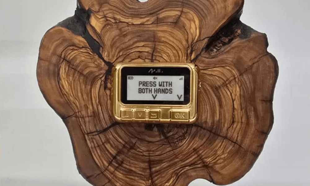 pager dourado, com um escrito 'press with both hands'