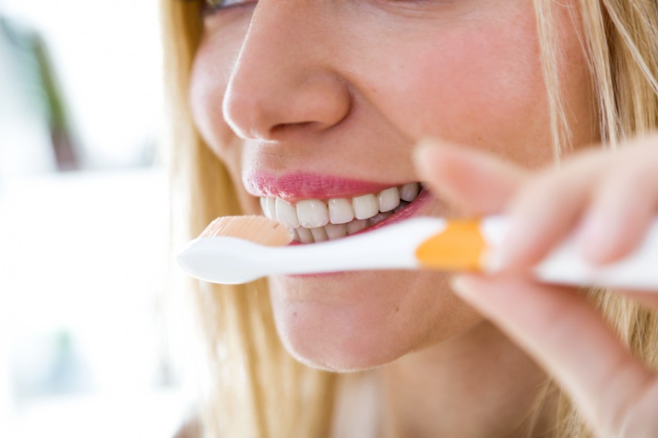Mulher loira limpando os dentes