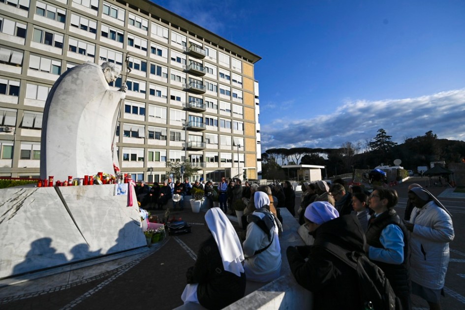 Fiéis rezam em frente à estátua do Papa João Paulo II na entrada do Hospital Gemelli, onde o Papa Francisco está internado, em Roma