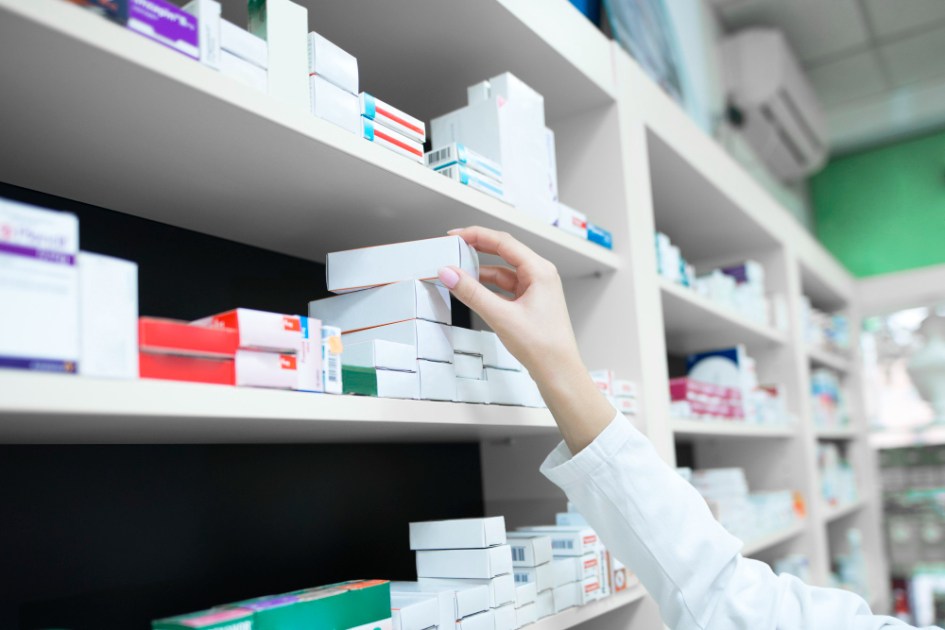 loseup vista da mão do farmacêutico tirando a caixa de remédios da prateleira da farmácia