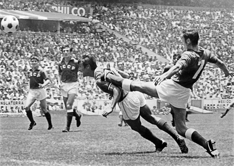 O atacante mexicano Horacio López Salgado (C) cabeceia de peixinho sob pressão do defensor da União Soviética Gennadi Logofet (D) durante a partida de abertura da Copa do Mundo