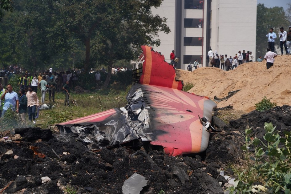 Pessoas observam os destroços no local de um acidente aéreo próximo ao Aeroporto Internacional Sardar Vallabhbhai Patel, em Ahmedabad