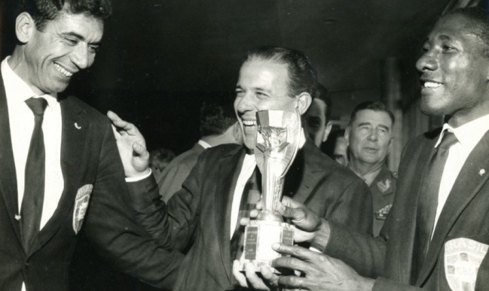O presidente Jango recebe a seleção brasileira após o título mundial e, entre Nilton Santos e Djalma Santos, segura nas mãos a Jules Rimet