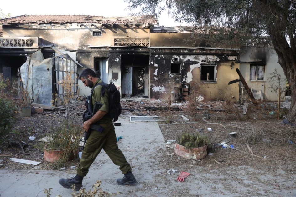 Um soldado israelense passa por uma casa em ruínas no Kibutz Beeri, perto da fronteira com Gaza