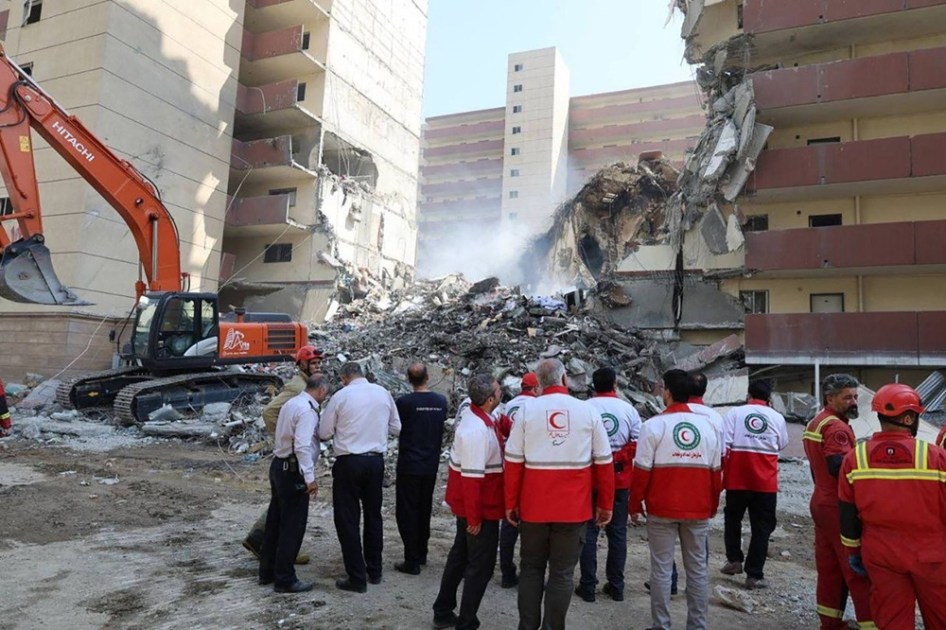 Voluntários do Crescente Vermelho Iraniano se reúnem em frente a um prédio destruído por um ataque israelense em Teerã
