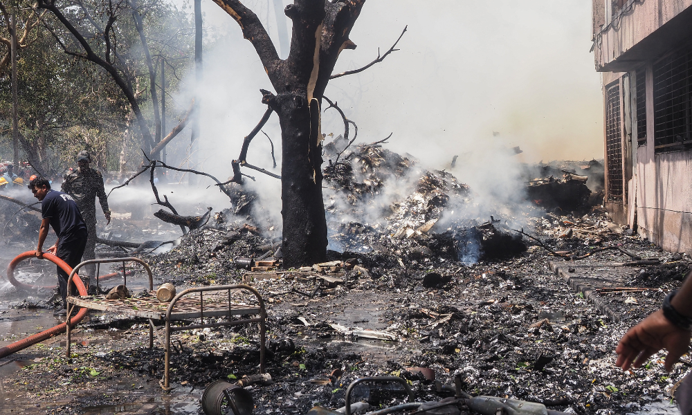 Bombeiros trabalham no local onde o voo 171 da Air India caiu em uma área residencial próxima ao aeroporto de Ahmedabad, em 12 de junho de 2025. O avião de passageiros, com destino a Londres, caiu na cidade de Ahmedabad, no oeste da Índia, com 242 pessoas a bordo, segundo autoridades da aviação, em um acidente que a companhia aérea classificou como "tragédia". (Foto: Sam Panthaky / AFP)