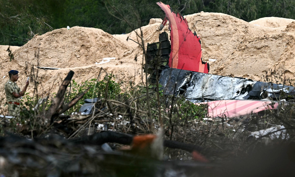 FOTOGRAFIA PRINCIPAL - Um policial monta guarda perto dos destroços do voo 171 da Air India após a queda em uma área residencial perto do aeroporto de Ahmedabad em 13 de junho de 2025. Equipes de resgate com cães farejadores vasculharam o local do acidente em 13 de junho de um jato de passageiros com destino a Londres que caiu em uma área residencial da cidade de Ahmedabad, na Índia, matando pelo menos 265 pessoas a bordo e no solo. (Foto de Punit PARANJPE / AFP)