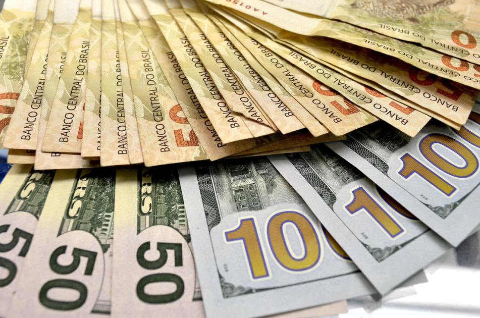 Cédulas de dólar e real espalhadas