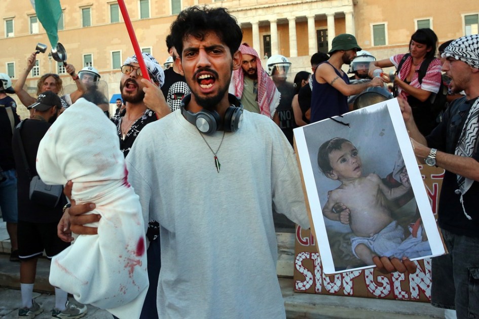 Manifestantes seguram fotos de crianças famintas de Gaza durante um protesto pró-Palestina em Atenas