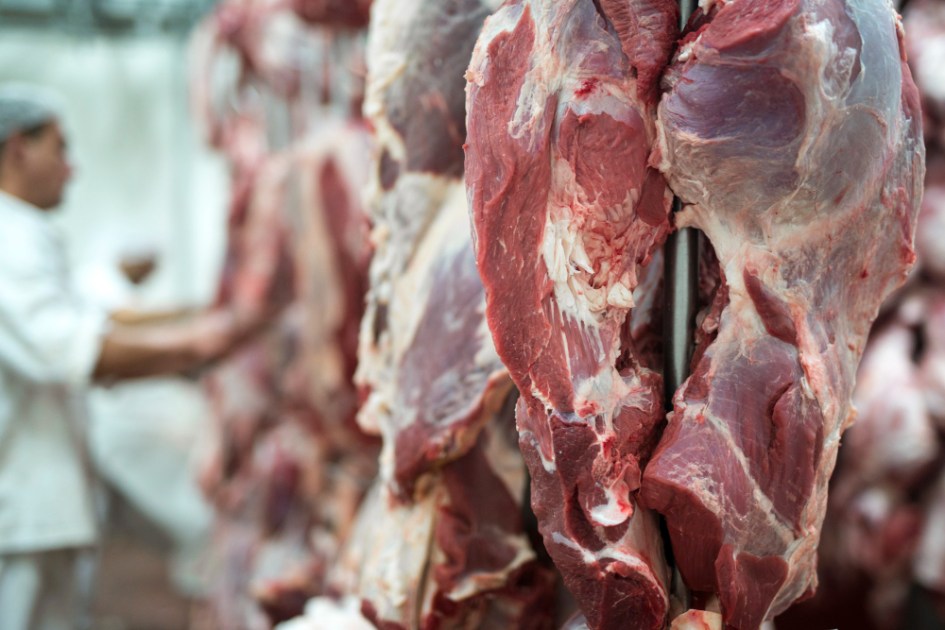 Carne vermelha fresca, e trabalhador de talho trabalhando em segundo plano