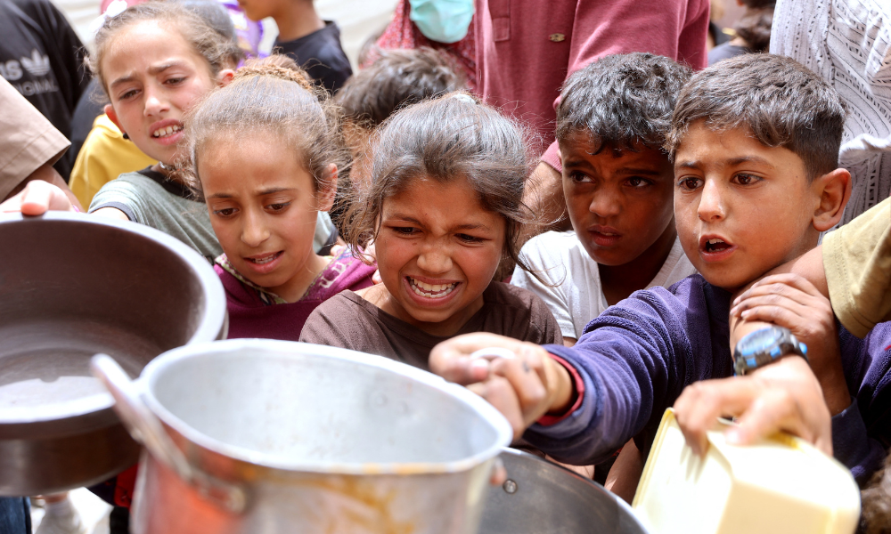 Crianças palestinas fazem fila para uma refeição quente em uma cozinha beneficente na Cidade de Gaza, em 30 de abril de 2025. A agência de alimentos da ONU, uma das principais fornecedoras de assistência alimentar no território palestino sitiado, informou em 25 de abril que havia "entregado seus últimos estoques de alimentos para cozinhas de refeições quentes na Faixa de Gaza", onde Israel bloqueou toda a ajuda por mais de sete semanas, acrescentando que "essas cozinhas devem ficar sem comida nos próximos dias". (Foto de Omar AL-QATTAA / AFP)