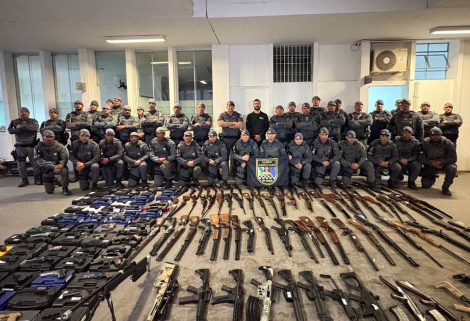 Policiais posam com armas apreendidas, entre fuzis, revólveres, pistolas, carabinas e espingardas