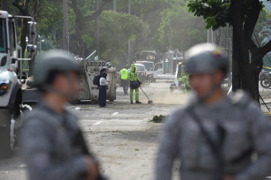 Funcionários de limpeza recolhem escombros em uma rua próxima à Escola Militar de Aviação Marco Fidel Suárez