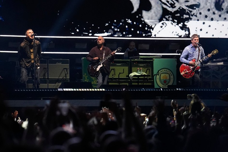 Liam Gallagher (vocalista), Paul Arthurs (guitarrista) e Noel Gallagher (vocalista e guitarrista) da banda britânica Oasis se apresentam no Principality Stadium, em Cardiff