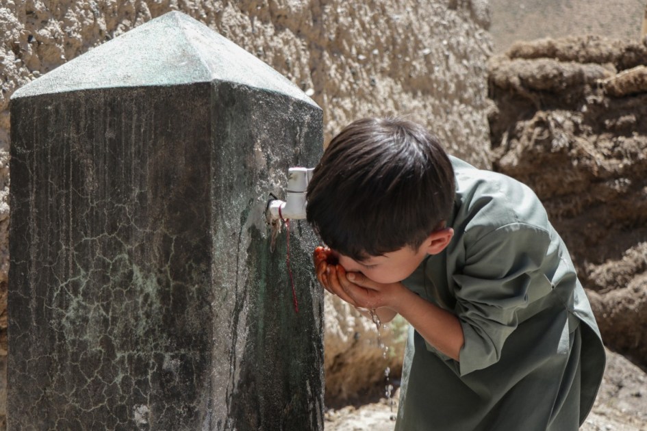Menino afegão bebe água de uma torneira na aldeia de Qavariyak, no distrito de Shibar, na província de Bamiyan