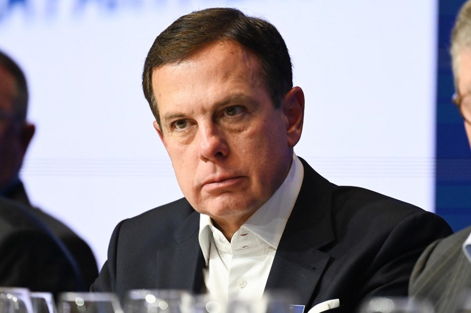 João Doria sentado em sala durante evento