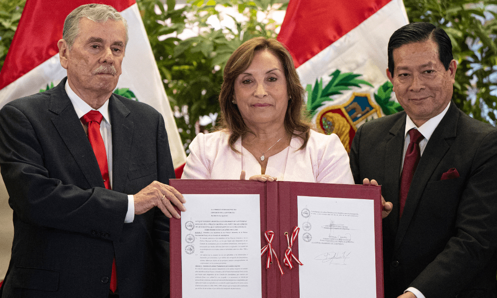 A presidente do Peru, Dina Boluarte (C), mostra o documento assinado ao lado do presidente do Gabinete, Eduardo Arana (D), e do vice-presidente do Congresso, Fernando Rospigliosi (E), durante uma cerimônia de promulgação de uma lei de anistia para militares e policiais processados por violações de direitos humanos no Palácio do Governo em Lima, em 13 de agosto de 2025. A presidente peruana, Dina Boluarte, promulgou na quarta-feira uma polêmica lei de anistia para militares e policiais processados por violações de direitos humanos durante o conflito armado que devastou o país entre 1980 e 2000. (Foto de Ernesto BENAVIDES / AFP)