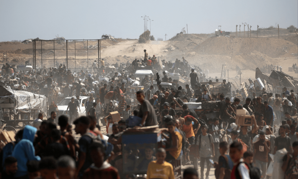 Palestinos deixam um ponto de distribuição de alimentos administrado pela Fundação Humanitária de Gaza (GHF), apoiada pelos EUA e por Israel, com sacolas e paletes de madeira, perto do corredor de Netsarim, no centro da Faixa de Gaza, em 3 de agosto de 2025. Agências humanitárias alertaram que a população de Gaza enfrenta uma fome catastrófica, desencadeada pelas restrições israelenses à ajuda. (Foto de Eyad BABA / AFP)