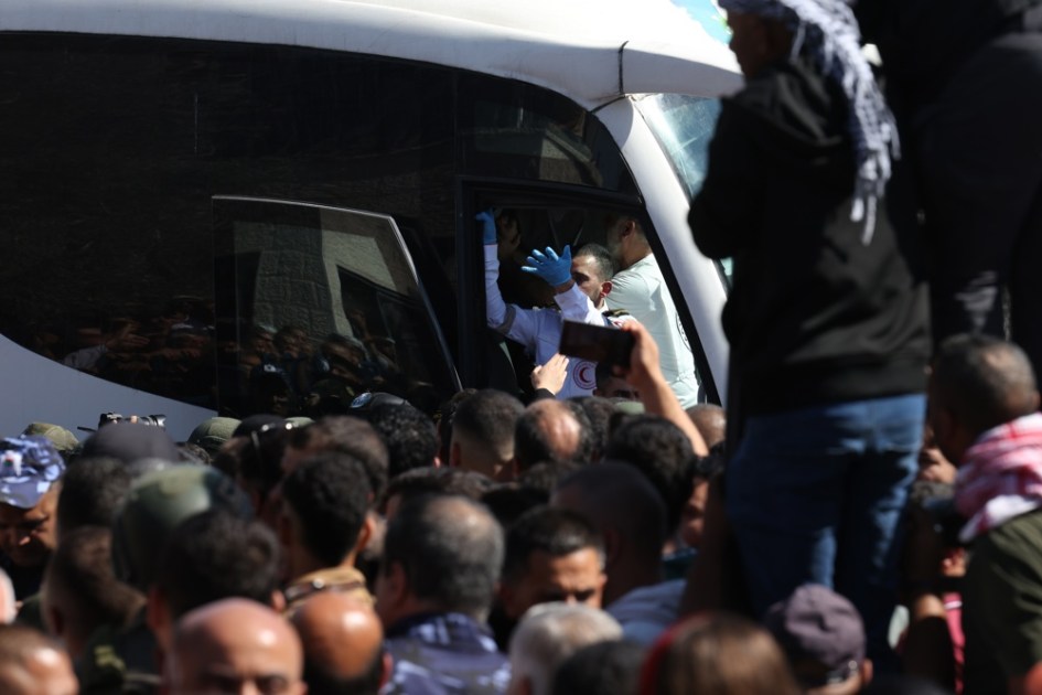 Um membro do Crescente Vermelho gesticula de dentro de um ônibus que transportava prisioneiros palestinos libertados ao chegarem após serem libertados de uma prisão israelense como parte do acordo de libertação entre Israel e Hamas, na cidade de Ramallah, na Cisjordânia, em 13 de outubro de 2025. Como parte do acordo de cessar-fogo entre Israel e Hamas, cerca de 20 prisioneiros israelenses e cerca de 2.000 prisioneiros palestinos estão programados para serem libertados em 13 de outubro. (Ramala) EFE/EPA/ALAA BADARNEH