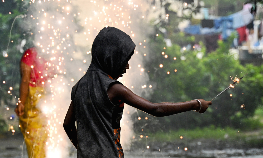 Um menino acende um fogo de artifício durante as celebrações na véspera de Diwali, o festival hindu das luzes, no alojamento de uma escola em Chennai, em 19 de outubro de 2025. (Foto de R. Satish BABU / AFP)