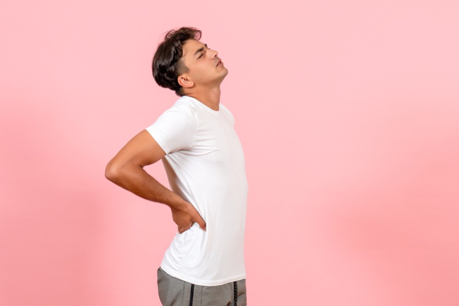 Vista frontal jovem do sexo masculino tendo dor nas costas na cor de fundo rosa modelo emoção masculino