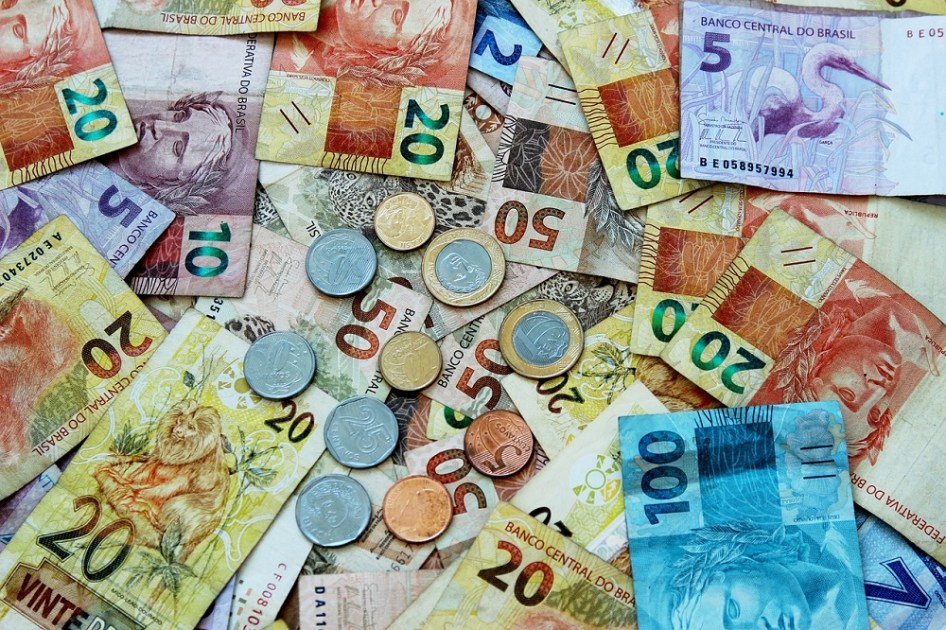 Dinheiro e moedas de real sobrepostos