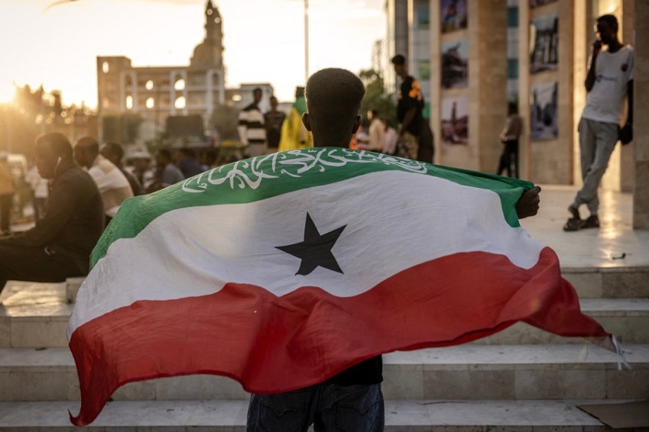 Homem segura a bandeira da Somalilândia em frente ao Memorial da Guerra de Hargeisa