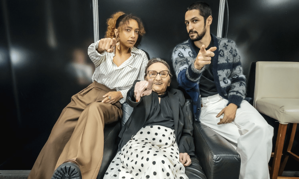 Tânia Maria, Gabriel Leone e Alice Carvalho sentados em poltrona apontando para câmera