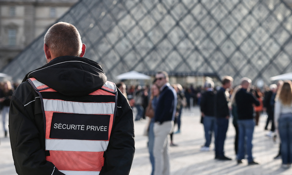Um segurança em frente à Pirâmide do Louvre, projetada pelo arquiteto sino-americano Ieoh Ming Pei, com o Museu do Louvre ao fundo, em Paris, em 22 de outubro de 2025. O Museu do Louvre reabriu suas portas aos visitantes na manhã de 22 de outubro de 2025, pela primeira vez desde o roubo espetacular de 19 de outubro de 2025 por quatro criminosos, que levaram oito joias avaliadas em cerca de € 88 milhões, informou um jornalista da AFP.