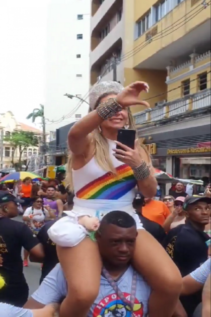 Carla Perez nos ombros de segurança negro