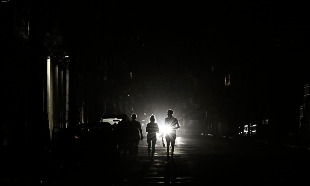 Pessoas caminham por uma rua sem eletricidade durante o apagão nacional em Havana