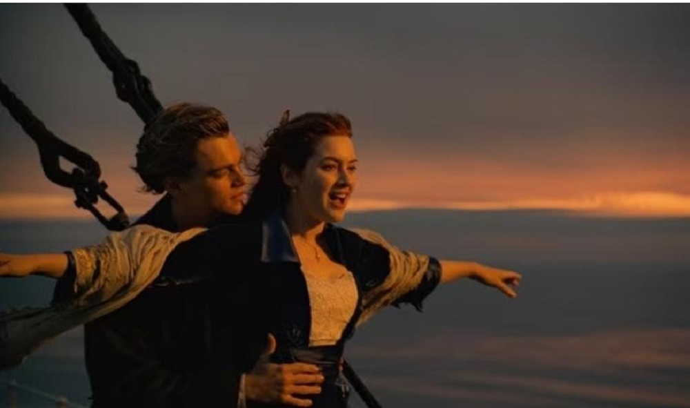 Cena clássica do filme Titanic com os personagens na frente do navio com os braços abertos