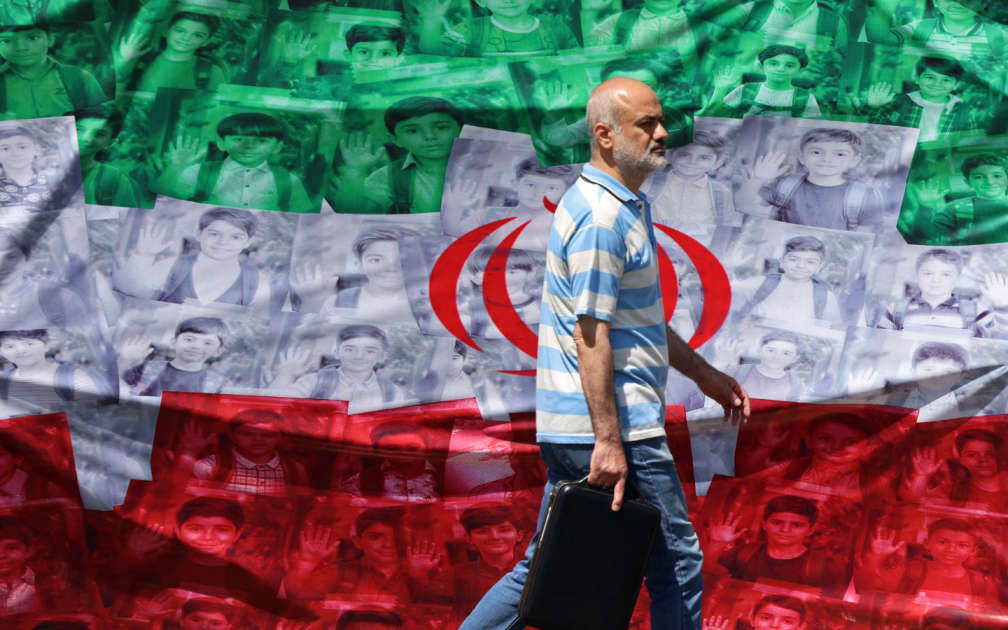 A man walks past an Iranian flag installed along the roadside in Tehran on April 29, 2026, depicting images of children killed on the first day of the war in an alleged US-Israeli missile strike on a school in the southern Iranian city of Minab. US President Donald Trump on April 29 warned Iran to "better get smart soon" as efforts by Washington and Tehran to end hostilities appeared at a standstill.