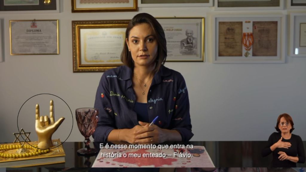 Michelle com o sinal do 'eu te amo' em Libras circulado na imagem