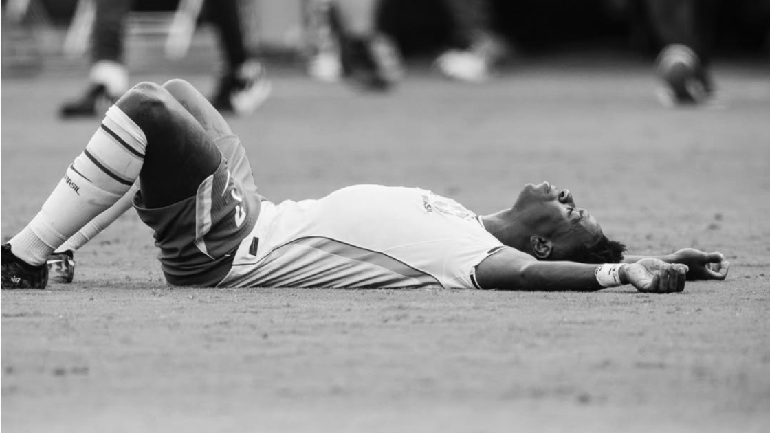 Atacante Vini Jr deitado no gramado após a eliminação do Brasil para a Noruega.