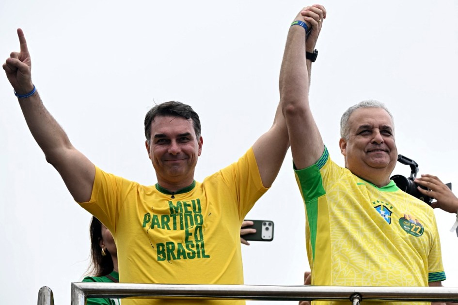O senador e candidato presidencial de direita do Brasil, Flávio Bolsonaro, e seu candidato a vice, o deputado Alfredo Gaspar, acenam durante um comício na praia de Copacabana, no Rio de Janeiro, em 16 de agosto de 2026